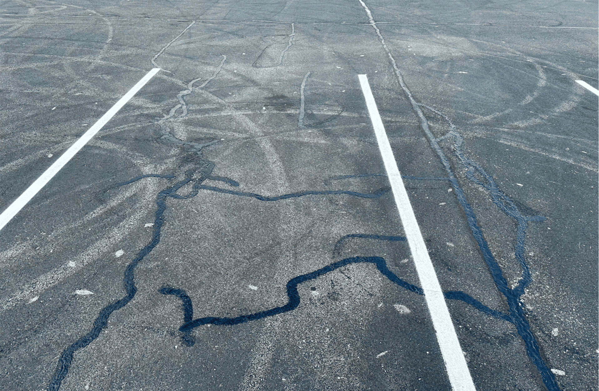 Close-up view of an asphalt parking lot with crack filling applied to repair surface cracks