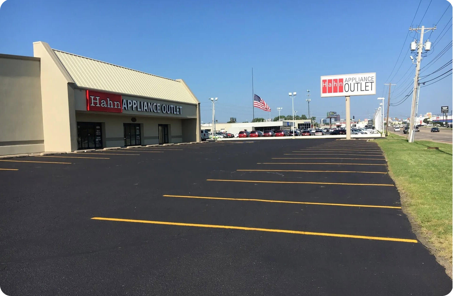 Freshly paved asphalt parking lot at Hahn Appliance Outlet with clear parking lines and American flag in the background