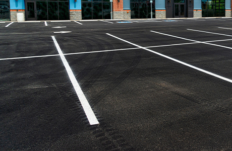 Freshly paved commercial parking lot with clear white line striping in front of a business building