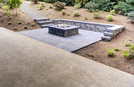 Beautiful modern concrete patio with fire pit, surrounded by landscaped garden with steps leading down to the patio area